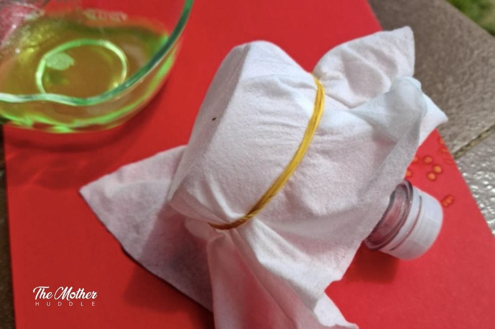 Place the wet wipe over the cut end of the bottle and use the elastic band to secure it